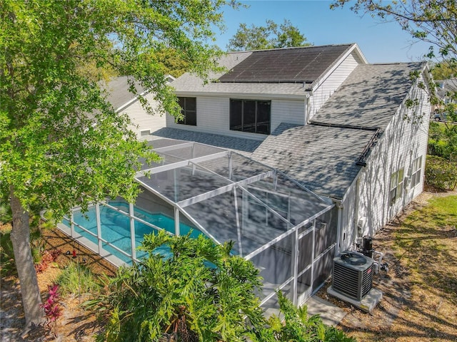 358 Morning Creek Cir, Apopka, FL 32712 - back of property featuring a lanai, central air condition unit, roof mounted solar panels, and a shingled roof