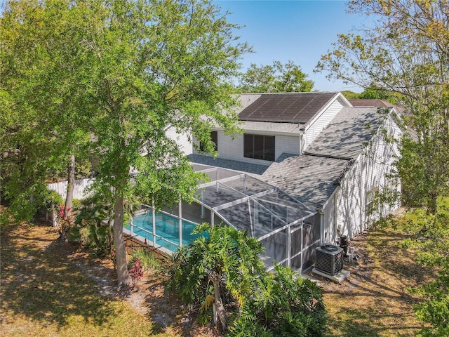 358 Morning Creek Cir, Apopka, FL 32712 - back of house with roof mounted solar panels, cooling unit, glass enclosure, a shingled roof, and an outdoor pool