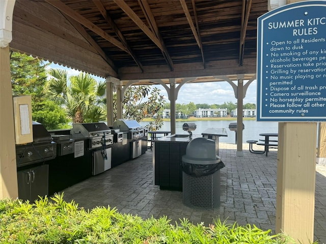 view of patio featuring grilling area, a water view, and an outdoor kitchen