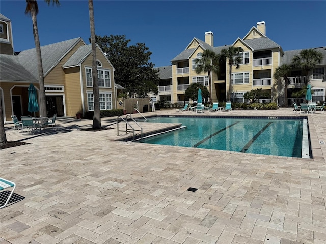 community pool with fence and a patio area