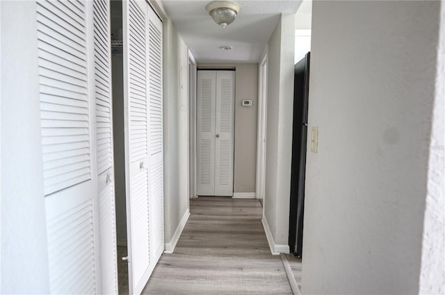 hallway with baseboards and light wood-style floors