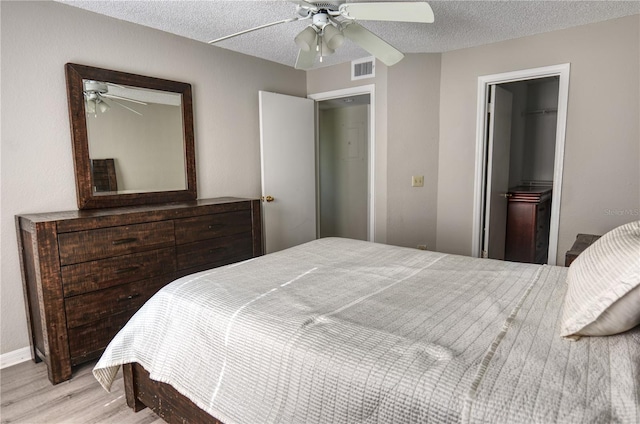 bedroom featuring wood finished floors, visible vents, a closet, and a textured ceiling