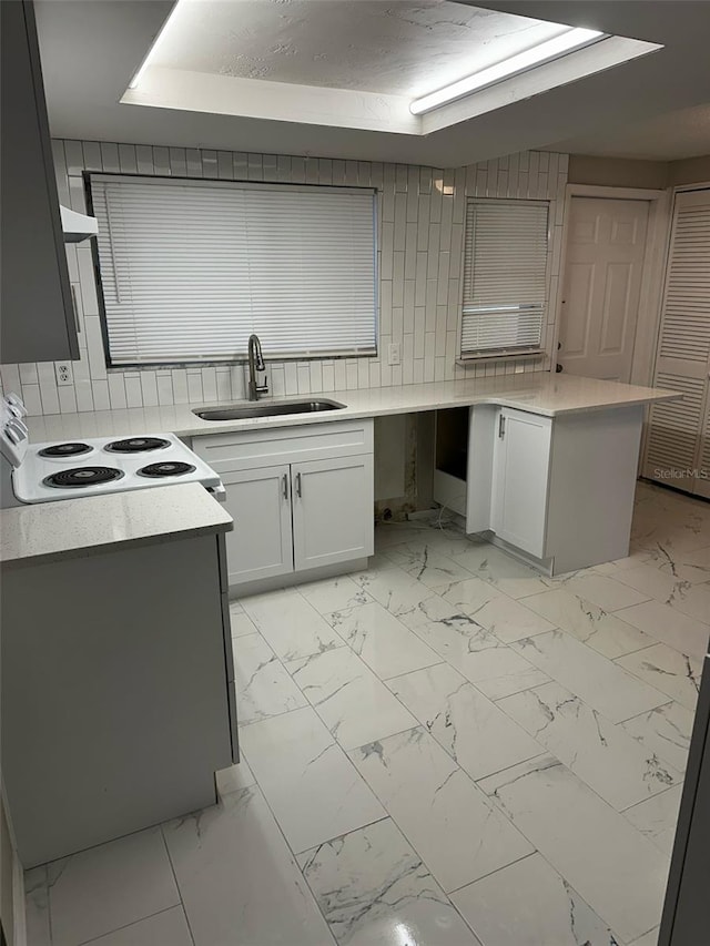kitchen featuring light countertops, decorative backsplash, white electric range oven, marble finish floor, and a sink