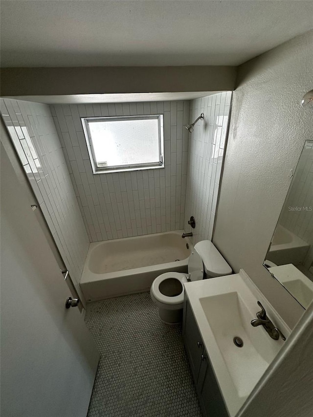 bathroom with tile patterned floors, toilet,  shower combination, vanity, and a textured wall