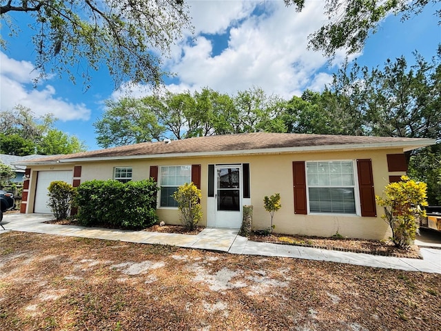 single story home with a garage, stucco siding, and concrete driveway