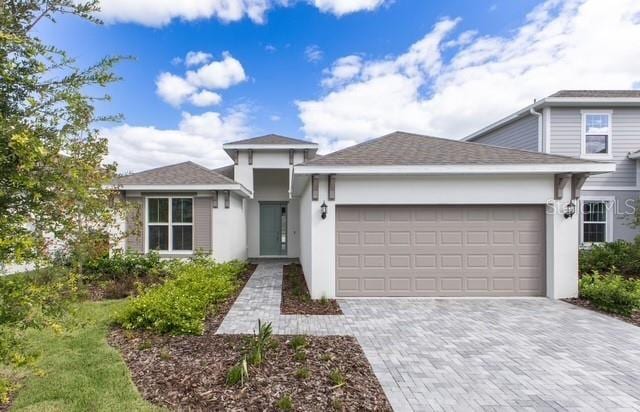 2296 Sirena Ln, Mount Dora, FL 32757 - view of front of house with a shingled roof, decorative driveway, an attached garage, and stucco siding