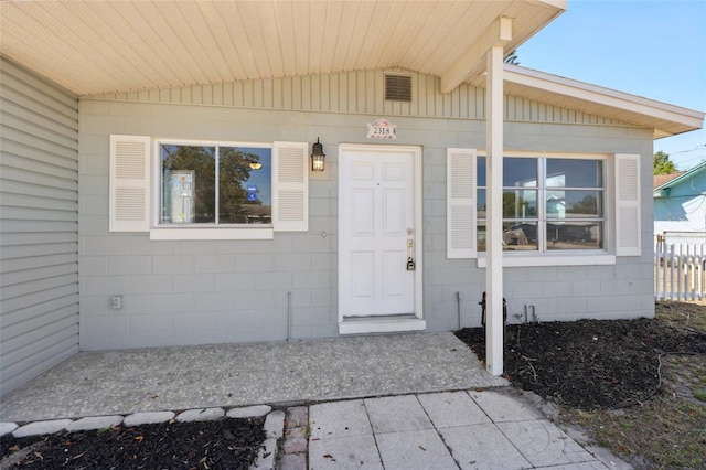 entrance to property featuring concrete block siding and fence
