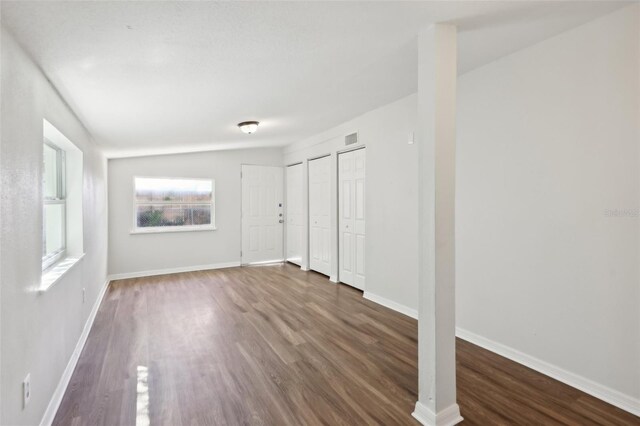 interior space featuring baseboards, visible vents, wood finished floors, and two closets