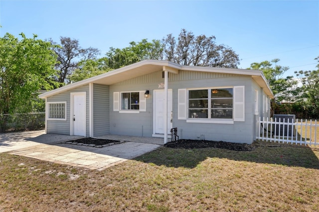 view of front of house with fence, a front lawn, and a patio area