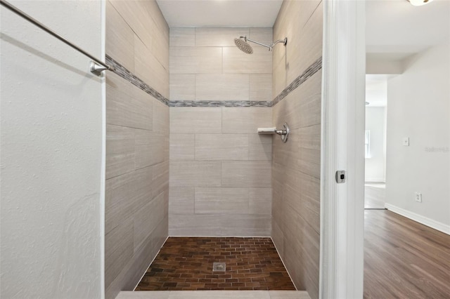 full bath with a tile shower and wood finished floors