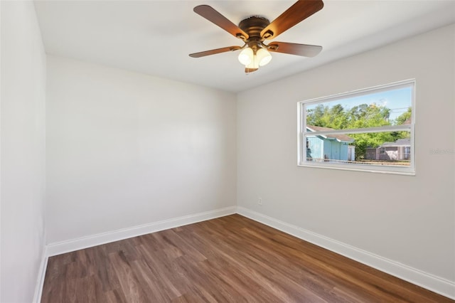 empty room featuring baseboards, ceiling fan, and dark wood-type flooring