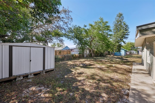 view of yard featuring a storage unit, an outdoor structure, and fence