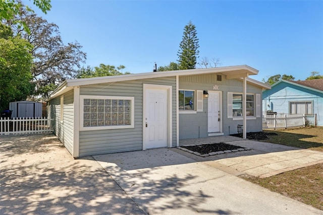 view of front of house with fence, a storage unit, and an outdoor structure