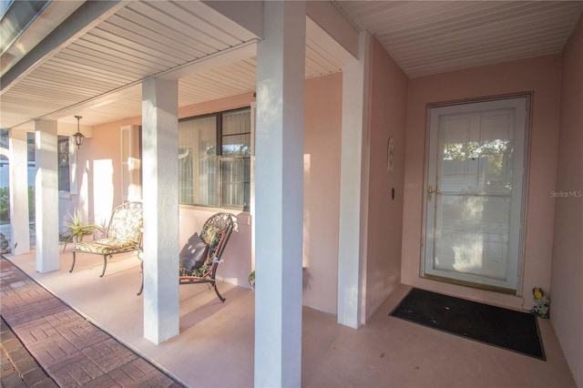 property entrance featuring covered porch and stucco siding