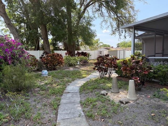 fenced backyard with a storage shed, an outdoor structure, and a sunroom