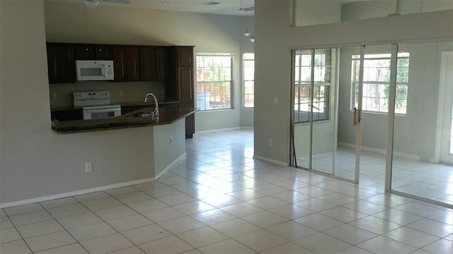 1760 Imperial Palm Dr, Apopka, FL 32712 - kitchen with light tile patterned flooring, a peninsula, white appliances, baseboards, and a sink
