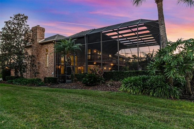 132 Pleasant Valley Dr, Daytona Beach, FL 32114 - back of house at dusk with a lanai, a yard, and a chimney