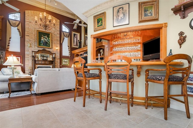 132 Pleasant Valley Dr, Daytona Beach, FL 32114 - tiled dining space with lofted ceiling, a brick fireplace, ceiling fan with notable chandelier, and ornamental molding