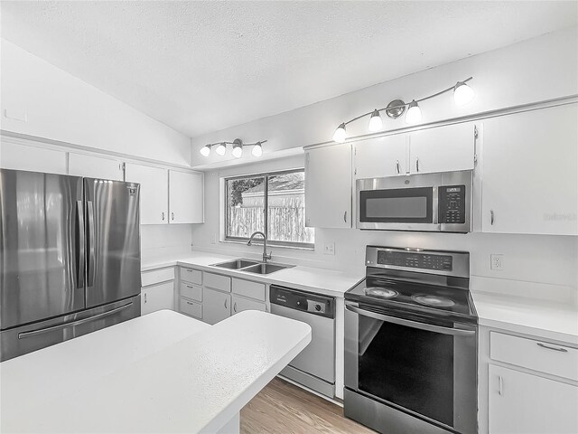 2253 Atrium Cir, Orlando, FL 32808 - kitchen with appliances with stainless steel finishes, a sink, light countertops, lofted ceiling, and a textured ceiling
