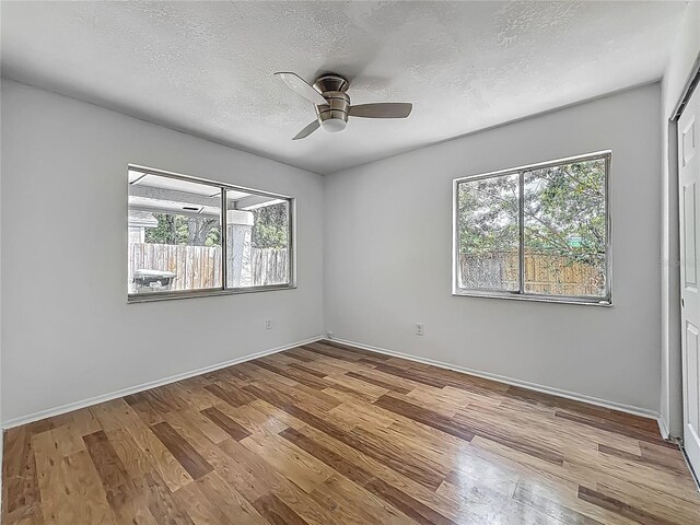 2253 Atrium Cir, Orlando, FL 32808 - spare room featuring plenty of natural light, wood finished floors, a textured ceiling, a ceiling fan, and baseboards