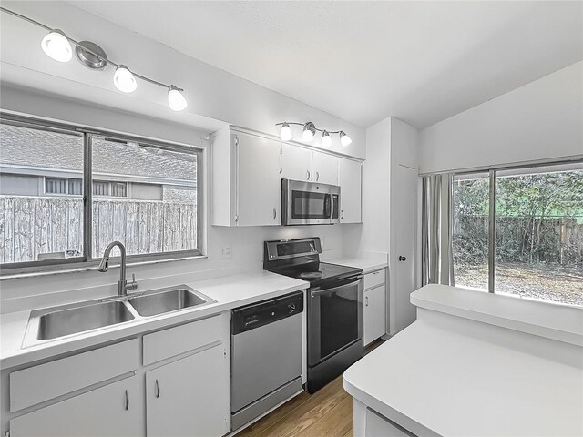 2253 Atrium Cir, Orlando, FL 32808 - kitchen with appliances with stainless steel finishes, a sink, light countertops, wood finished floors, and white cabinetry