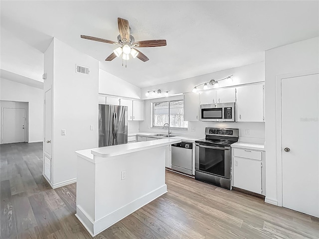2253 Atrium Cir, Orlando, FL 32808 - kitchen with stainless steel appliances, lofted ceiling, a sink, light wood-type flooring, and light countertops