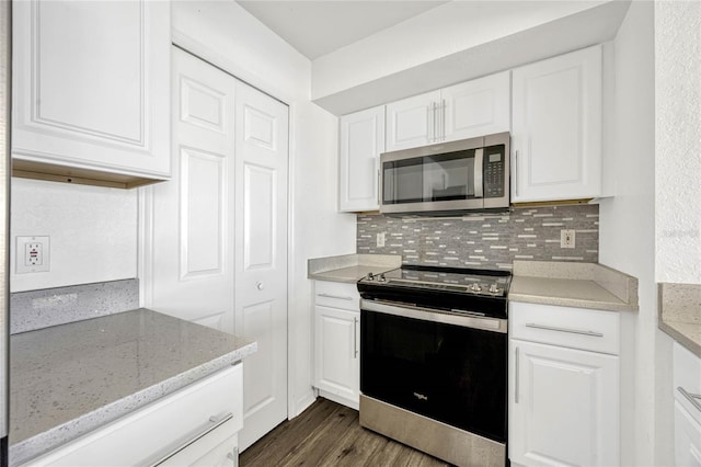 2314 Midtown Ter Unit 1136, Orlando, FL 32839 - kitchen featuring dark wood-type flooring, stainless steel microwave, backsplash, range with electric stovetop, and white cabinets