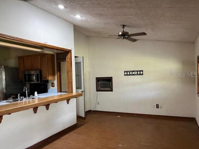 271 Naylor St NE, Palm Bay, FL 32907 - kitchen with stainless steel microwave, ceiling fan, freestanding refrigerator, baseboards, and brown cabinets