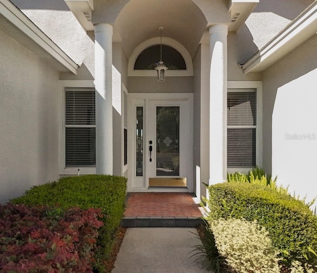 doorway to property with stucco siding and visible vents