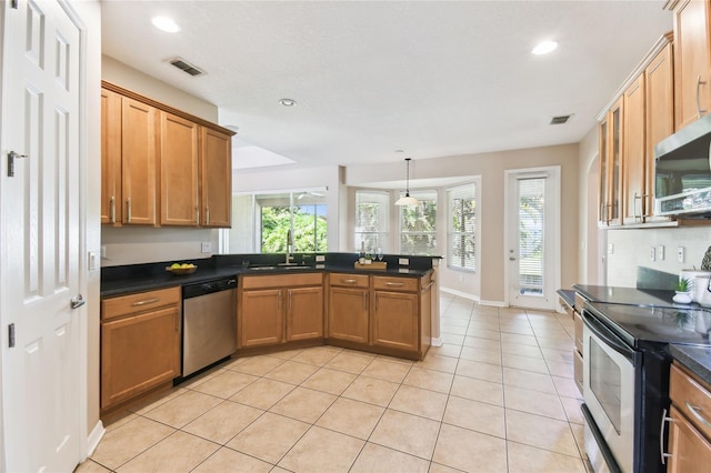 kitchen with stainless steel appliances, a sink, dark countertops, visible vents, and a peninsula
