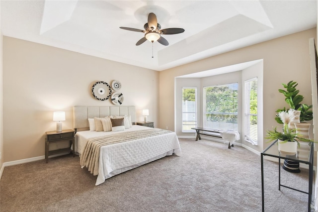 bedroom with a tray ceiling, baseboards, ceiling fan, and carpet floors