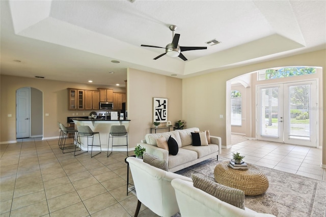 living area with visible vents, arched walkways, and a raised ceiling