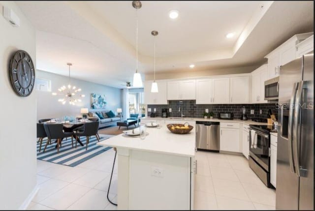 kitchen featuring light tile patterned floors, decorative backsplash, appliances with stainless steel finishes, a raised ceiling, and open floor plan