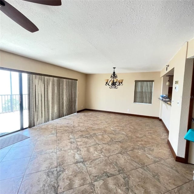 unfurnished room with ceiling fan with notable chandelier, baseboards, and a textured ceiling