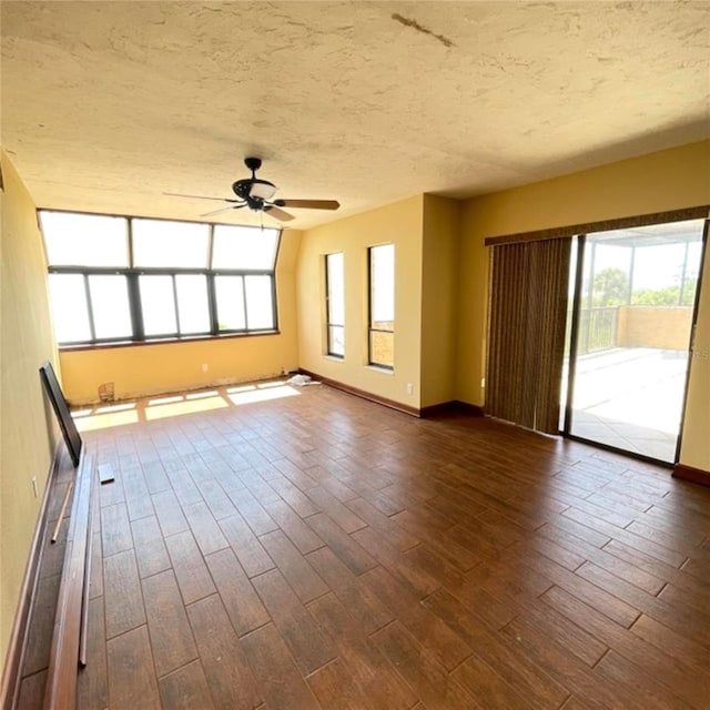 interior space with dark wood-style floors, baseboards, a textured ceiling, and a ceiling fan