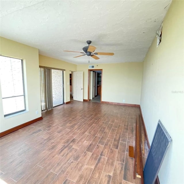 unfurnished room featuring ceiling fan, baseboards, a textured ceiling, and wood finished floors