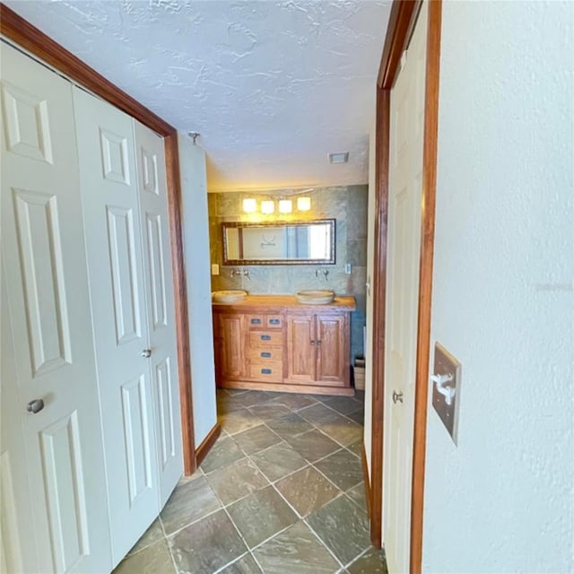 hallway with visible vents, a textured ceiling, and stone finish floor