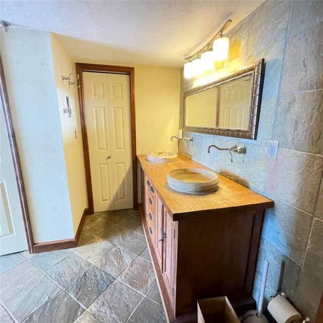 full bathroom with tile walls, double vanity, and a sink