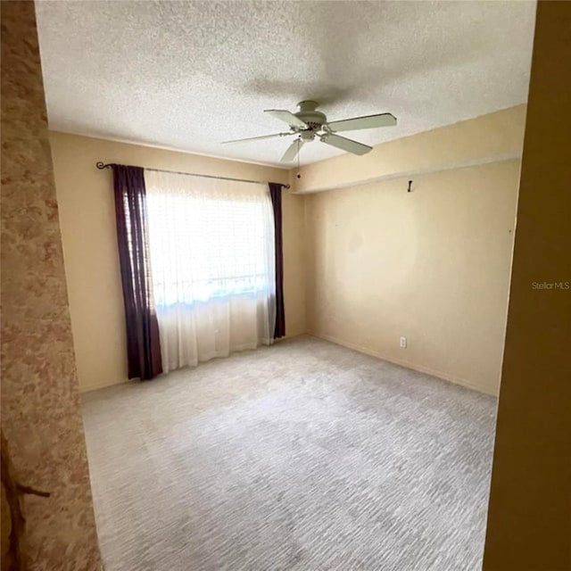 carpeted spare room with a textured ceiling and a ceiling fan