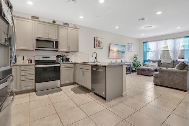 11038 Leafshore Loop, Orlando, FL 32829 - kitchen featuring stainless steel appliances, a peninsula, gray cabinetry, open floor plan, and recessed lighting