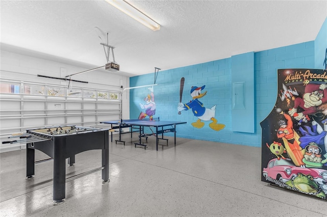 501 Burma St, Kissimmee, FL 34747 - rec room featuring concrete block wall, a textured ceiling, speckled floor, and a garage