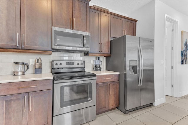 501 Burma St, Kissimmee, FL 34747 - kitchen featuring light tile patterned flooring, decorative backsplash, appliances with stainless steel finishes, and light countertops
