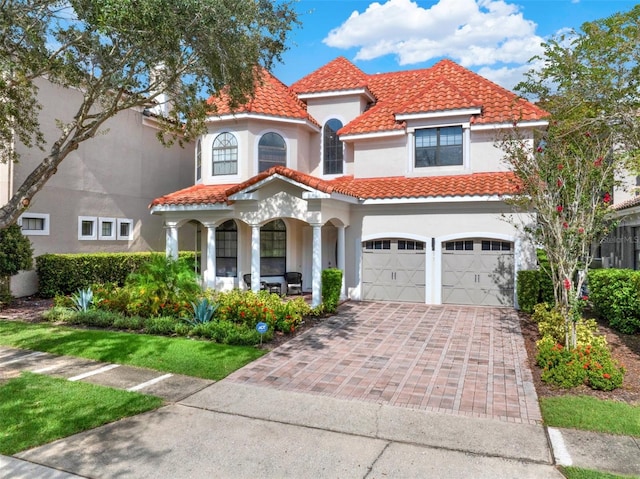 411 Muirfield Loop, Reunion, FL 34747 - mediterranean / spanish-style home with an attached garage, a tiled roof, stucco siding, a porch, and driveway
