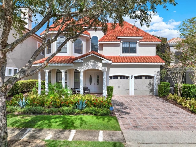 411 Muirfield Loop, Reunion, FL 34747 - mediterranean / spanish-style house featuring an attached garage, covered porch, a tiled roof, stucco siding, and driveway