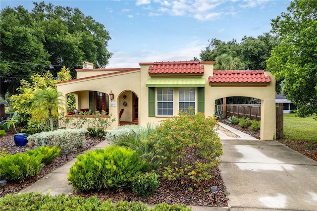 mediterranean / spanish home featuring a carport, stucco siding, concrete driveway, and fence