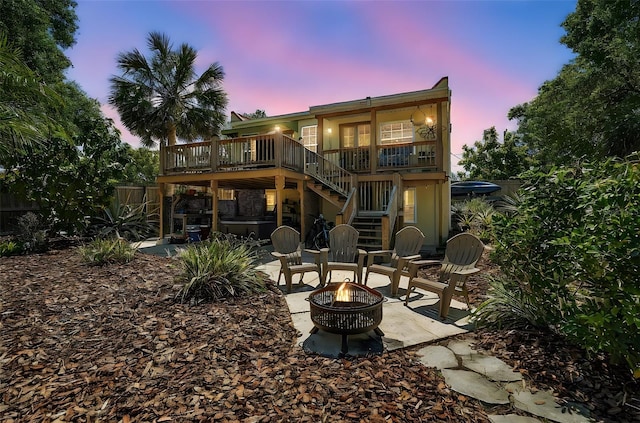 back of house at dusk with fence, stairway, an outdoor fire pit, a deck, and a patio area
