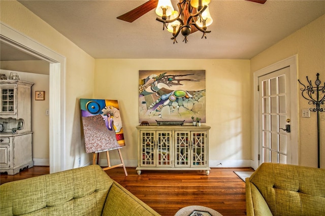 interior space with ceiling fan with notable chandelier, wood finished floors, baseboards, and a textured ceiling