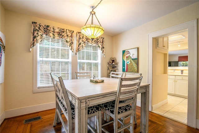 dining space with hardwood / wood-style flooring, baseboards, and visible vents