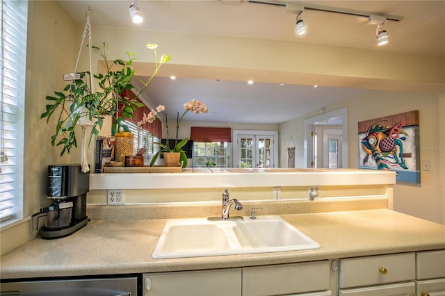 kitchen featuring white cabinets, dishwasher, light countertops, and a sink