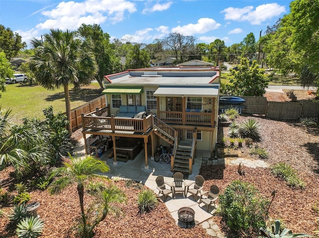 back of house featuring a patio, an outdoor fire pit, a fenced backyard, stairs, and a deck